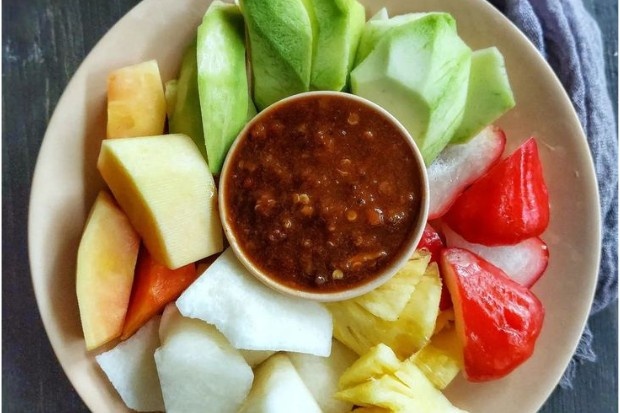 potongan rujak buah berisi mangga muda, nanas, jambu, dan bengkuang dengan bumbu khas yang menunjukkan isi rujak buah