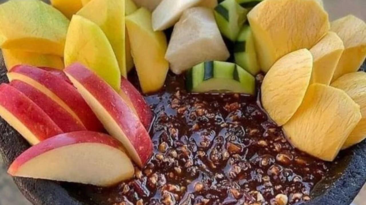 Rujak buah segar dengan potongan mangga, nanas, dan jambu disajikan dengan bumbu pedas manis yang menggugah selera